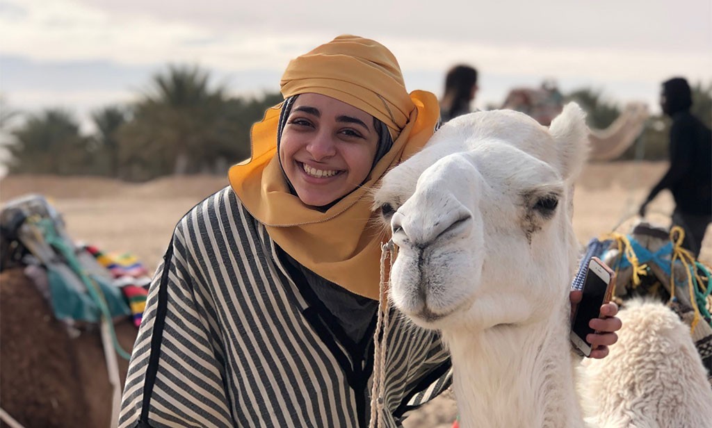 woman standing next to a camel