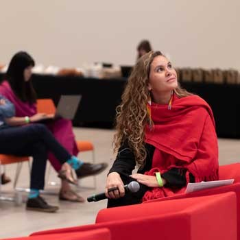 Flavia Maia, looking up at panelists during a discussion with participants in Brazil. Flavia Maia