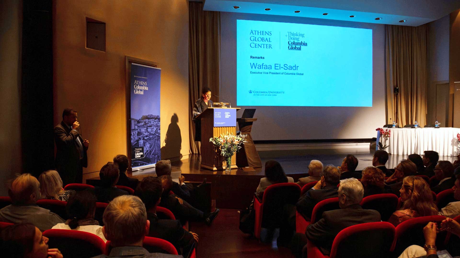 Speaker on a stage at the Athens lecture. 