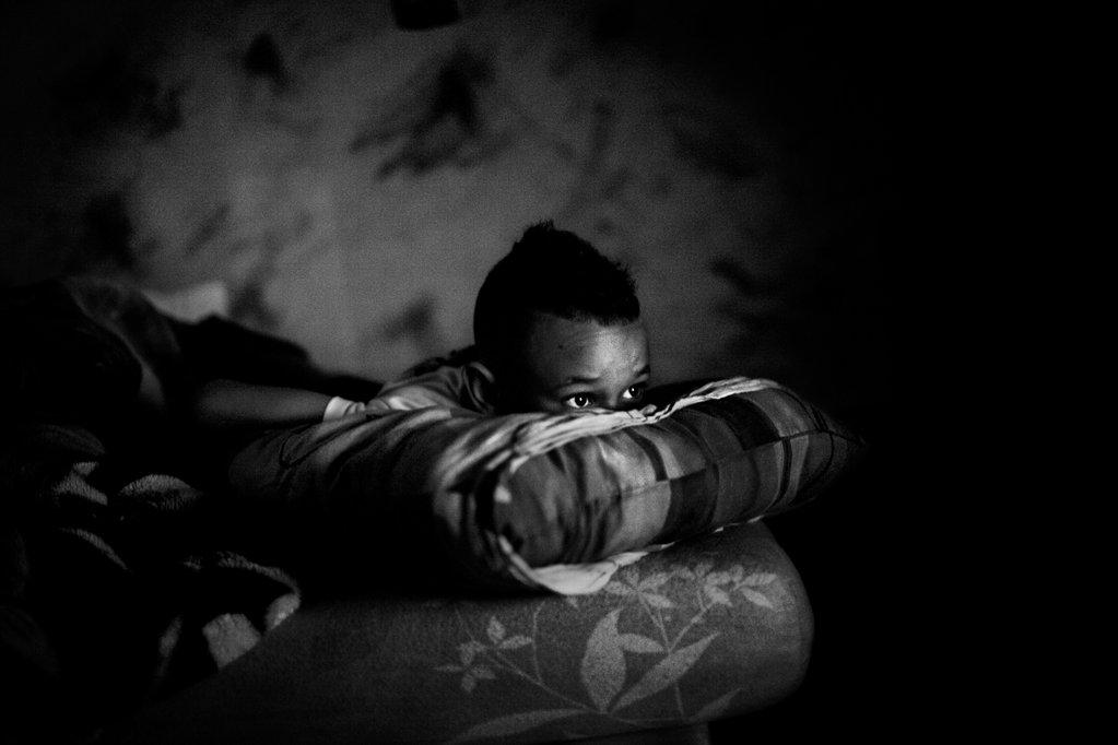 From Misrepresenting French Suburbia, Photo: Arnau Bach Black and white photo of a boy leaning his chin on pillows