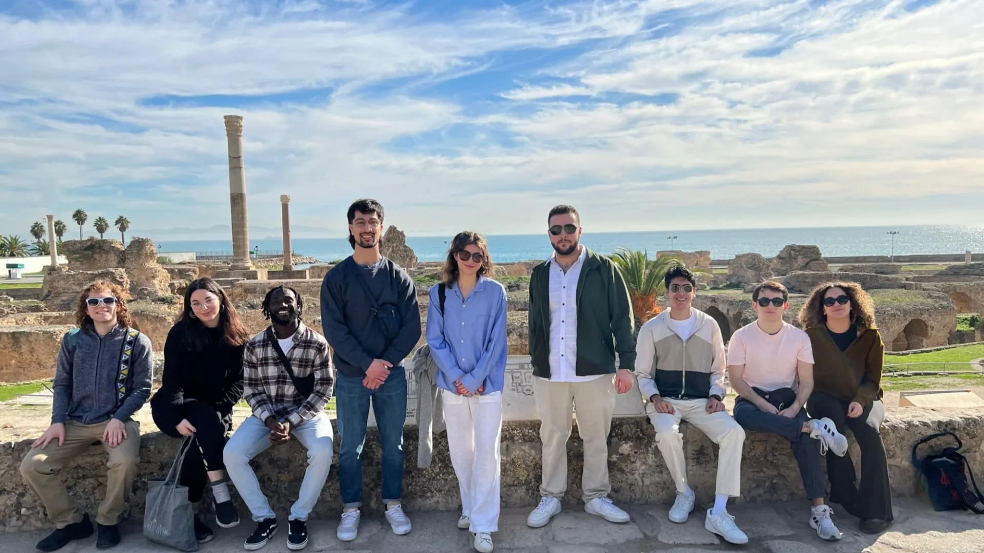A group of 9 students assembled for a group photo at the archaeological site of Carthage.