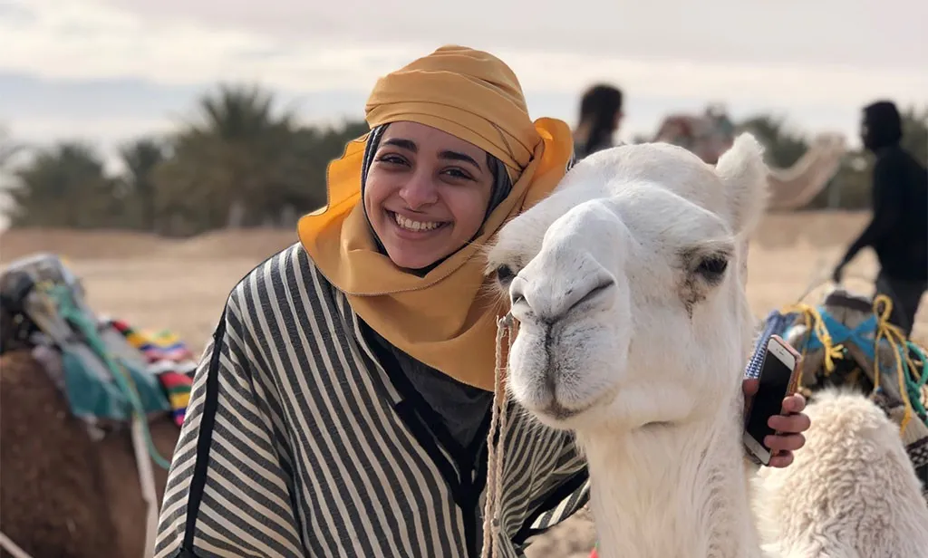 woman standing next to a camel