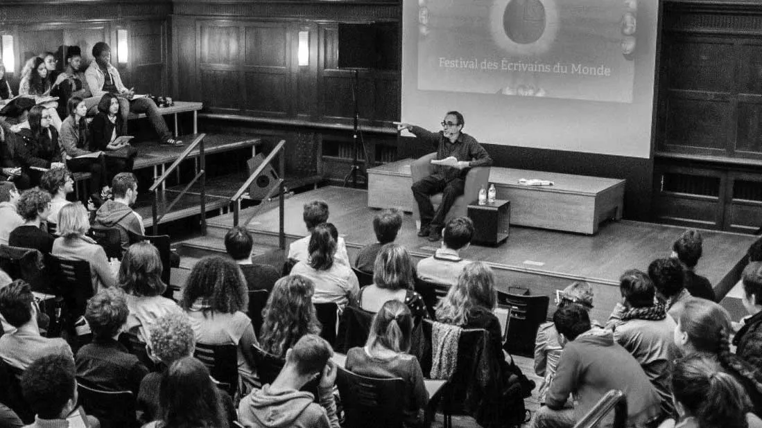 photo of public event with speaker on stage in front of a large audience