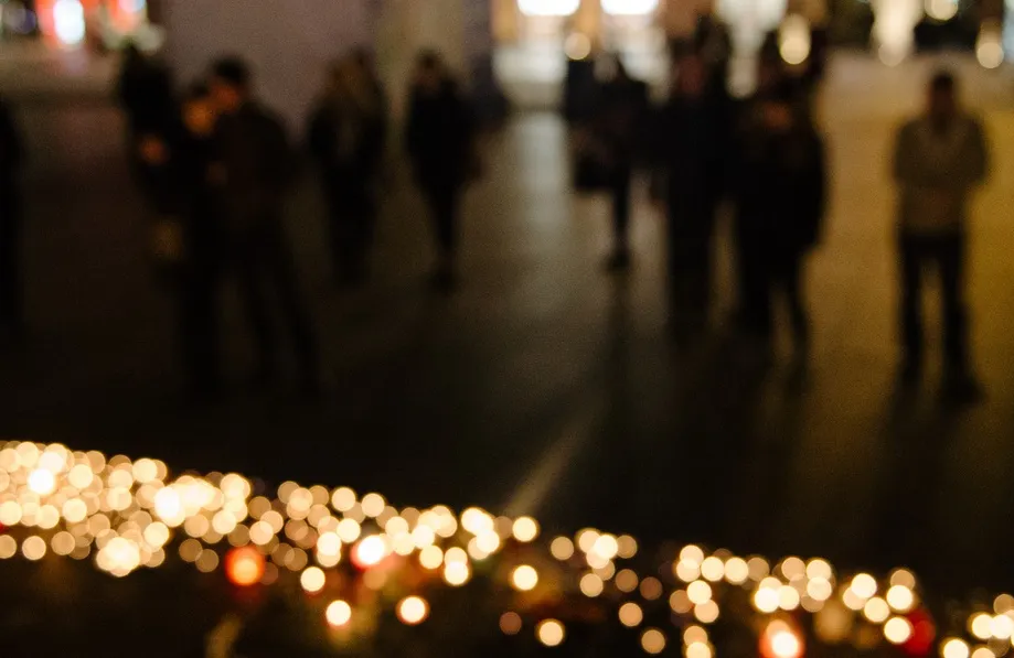 People standing outside in front of candles.