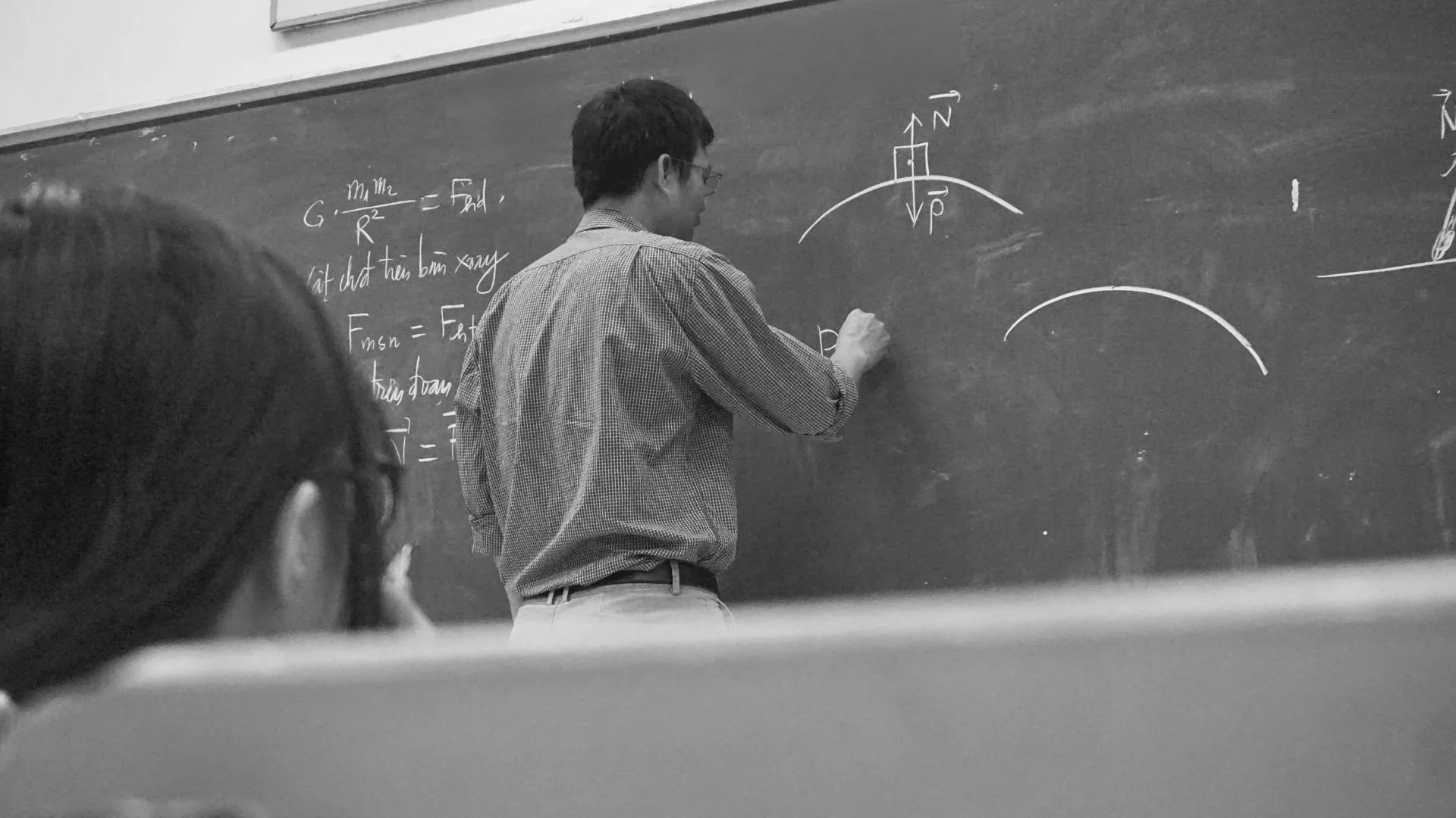 teacher writing on a blackboard in a classroom